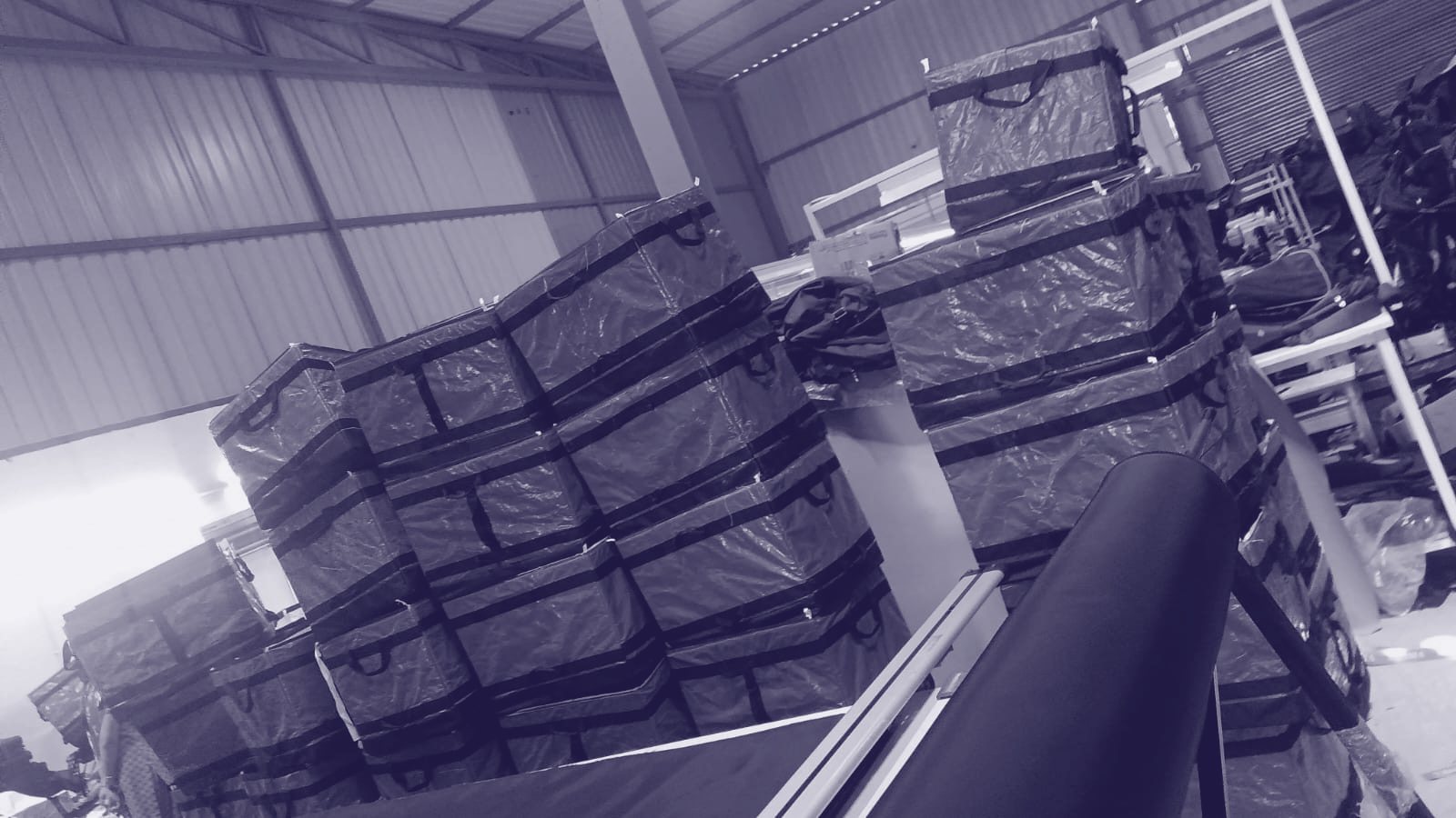 Zentara production floor in Haryana — stacks of finished carriers beside the cutting tables, duotone print